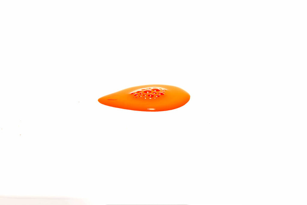 Orangefarbene Wassertropfen plätschern auf weißem Hintergrund - Foto, Bild