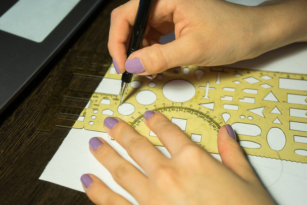 Girl with purple nails draws a circle with a ruler with figures - Foto, Bild