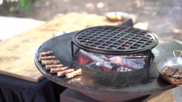 Szerb nemzeti étel - Chevapchichi. A húsos kolbászt egy lapos grillen sütik, középen tűzzel.. - Felvétel, videó