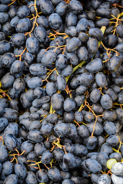 Lähikuva tuoreita sinisiä luonnonmukaisia viinirypäleitä pienessä puulaatikossa, joka on myynnissä katukaupassa - Valokuva, kuva