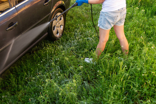 Lavagem de carro, uma mulher de luvas azuis lava um carro com um Karcher
 - Foto, Imagem