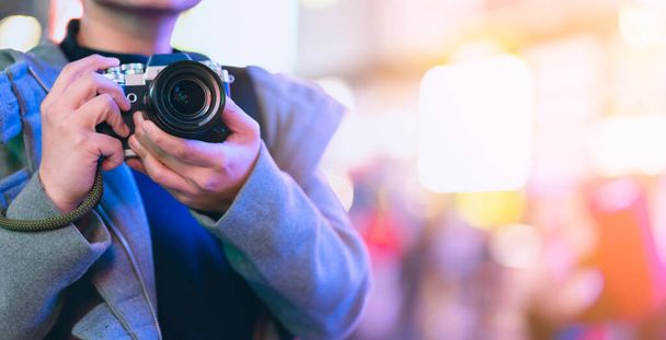 asian female traveller smile happiness hand hold mirrorless camera enjoy nightlife lifestyle tourost with light bokeh and crowd of people blur background in winter season close up banner size; - Foto, imagen