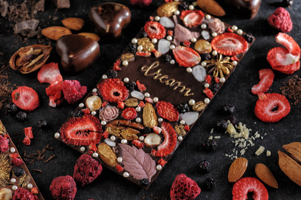 чорний шоколад з ручної роботи заморожують сушені ягоди та горіхи, натуральний на темному фоні, вид зверху
 - Фото, зображення