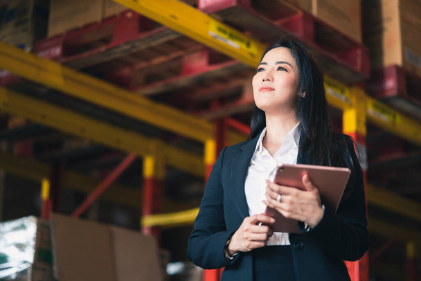 portrait of asian female business owner formal suit hand check product inventory stock with confident warehouse factory background  Business Investor deal and teamwork concept. - Photo, Image
