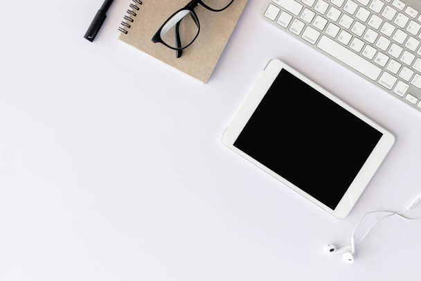Irodai munkahely szöveges hellyel, fehér fa asztal irodai kellékekkel tabletta, asztali számítógép és könyv, felülnézet, fényben - Fotó, kép