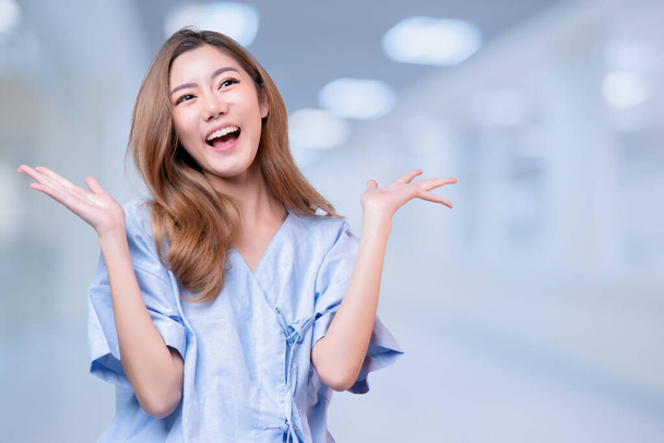 Goodnews gossip atttractive long hair asian female patient in hospital clinic uniform hand gestureexcited hearing happy message from somewhere blur clinic hospital background - Foto, afbeelding