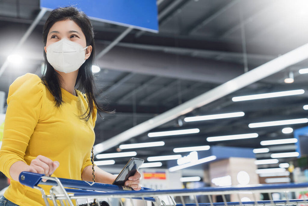 New normal lifestyle asian female yellow dress wear protecting mask shopping in department store after end of lockdown quarantine period - Фото, зображення