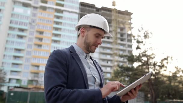 Inżynier budowlany w białym hełmie zmienia plany konstrukcyjne na tablecie - Materiał filmowy, wideo