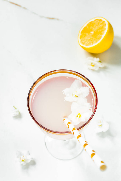 Şarap kadehinde kokteyl, pipet ve mor çiçekli limonlu hafif bir arka plan.. - Fotoğraf, Görsel