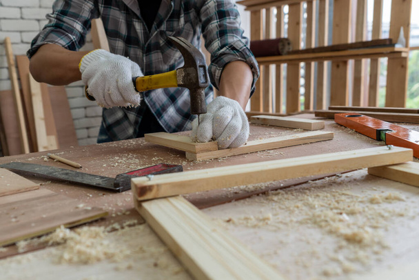 Ξυλουργός που εργάζεται σε ξυλουργείο για την παραγωγή οικοδομικών υλικών ή ξύλινων επίπλων. Ο νεαρός Ασιάτης ξυλουργός χρησιμοποιεί επαγγελματικά εργαλεία για χειροτεχνία. DIY maker και ξυλουργική έννοια εργασίας. - Φωτογραφία, εικόνα