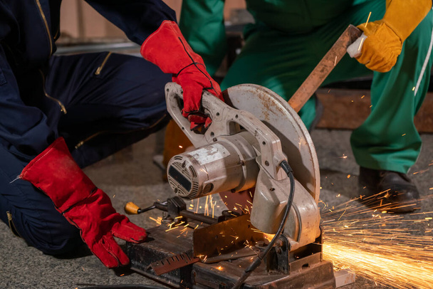 Un mécanicien professionnel coupe du métal d'acier avec un couteau rotatif à lame de carbone. Industrie sidérurgique et concept d'atelier. - Photo, image