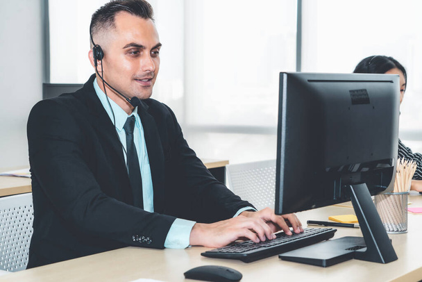 Business people wearing headset working in office to support remote customer or colleague. Call center, telemarketing, customer support agent provide service on telephone video conference call. - Foto, Imagen