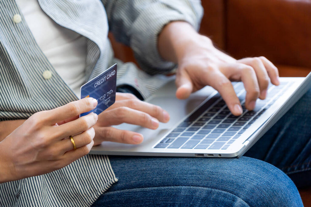 Mladý pár používá kreditní kartu pro on-line nakupování na internetových stránkách doma. Číslo na kreditní kartě je vzorový. Na kreditní kartě nejsou uvedeny žádné osobní údaje. Online obchodní nákupní koncept. - Fotografie, Obrázek