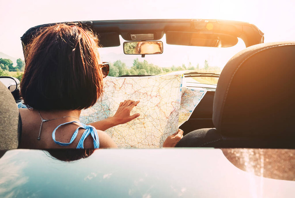 Woman reads roads map sitting in cabriolet car - Foto, immagini