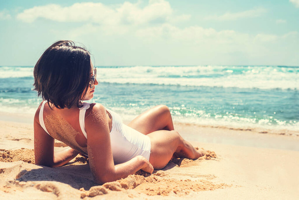 Woman takes a sun bath on tropical beach - Photo, Image