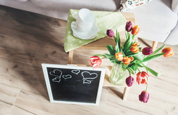 Cozy home spring atmosphere - vase with colorful tulips, chalk board and wooden chair - Foto, Imagem