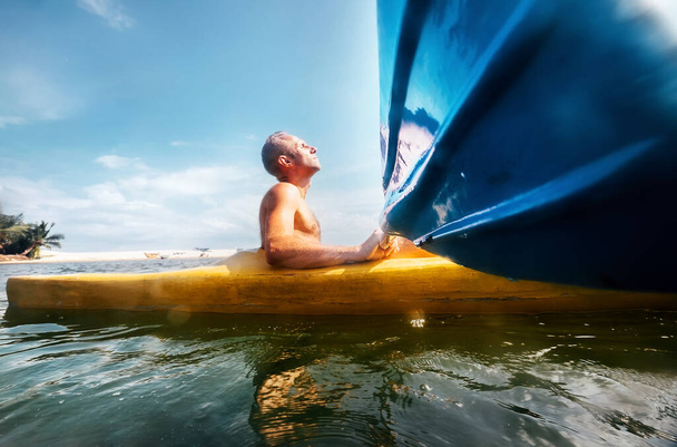 Man feeling the sun light on his face when he sails in canoe in tropical lagoon - Foto, afbeelding