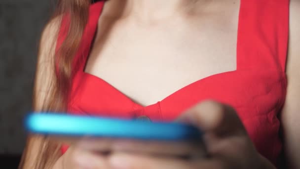 Το κορίτσι κάνει ψώνια μέσω της εφαρμογής Internet στο smartphone. Τηλέφωνο στο φόντο ενός γυναικείου στήθους. Επαγγελματικά και online μαθήματα εξ αποστάσεως. Κοντινό πλάνο - Πλάνα, βίντεο