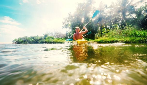 Man feeling the sun light on his face when he sails in canoe in tropical lagoon - Фото, изображение