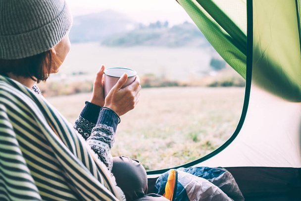 Woman with cup of hot tea sit in camping tent - Foto, immagini