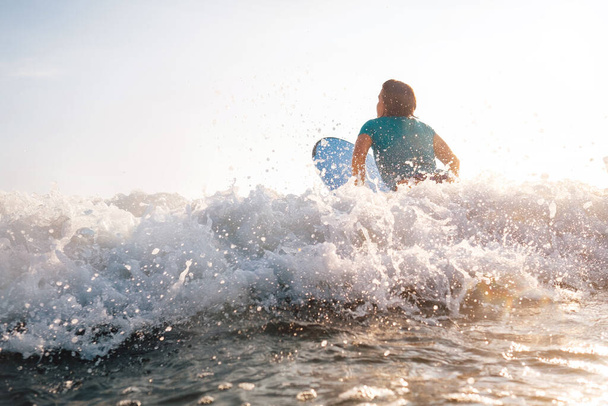 Woman on surfboard swims over the wave  - Valokuva, kuva