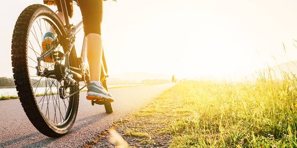 Woman feet on bycikle pedal in sunset light - Фото, зображення