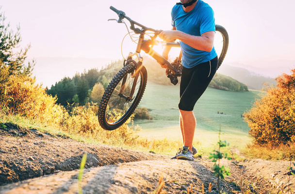  Ποδηλατικός-σταυρό μέλος του διαγωνισμού Man mountain bike κουβαλώντας το ποδήλατό του στην κορυφή του λόφου  - Φωτογραφία, εικόνα