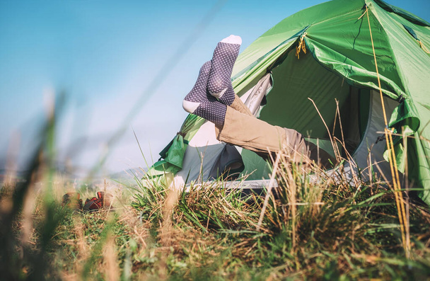 Traveler legs in socks stick out from camping tent - Fotoğraf, Görsel