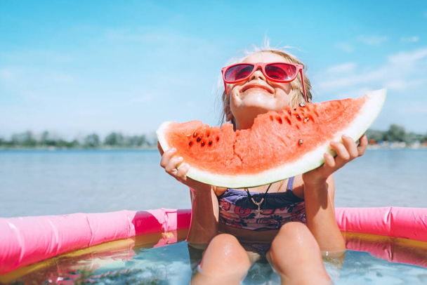 Little girl in pink sunglasses with bid watermelon segment funny - Foto, Imagen
