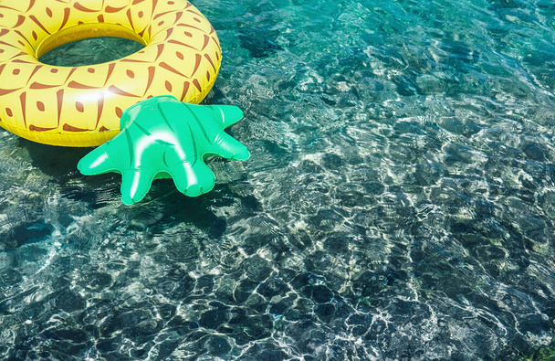 Crystal clear water in the sea lagoon with bright inflatable pineapple pool ring - Φωτογραφία, εικόνα