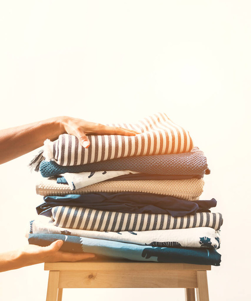 Woman hands take stack of blue and beige laundry - Zdjęcie, obraz