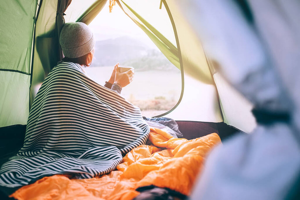 Alone Woman drinks hot tea in camping tent and enjoy with autumn evening in mountain valley - Photo, Image