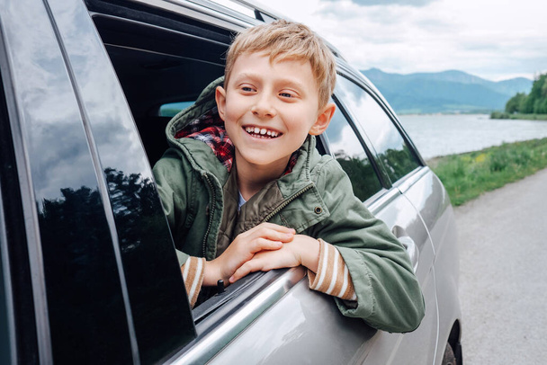 Happy boy look out from auto window - Foto, Imagen