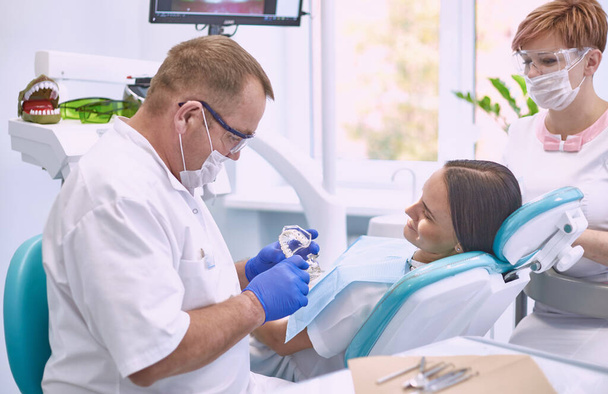 Médecin dentiste traite les dents d'une belle jeune fille patiente. La fille à la réception chez le dentiste. Médecin dentiste soigne les dents - Photo, image