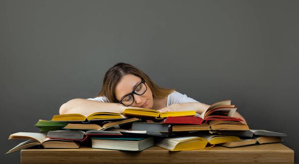 Ученица в очках, усердно учится и спит на книгах, усталая женщина в библиотеке - Фото, изображение