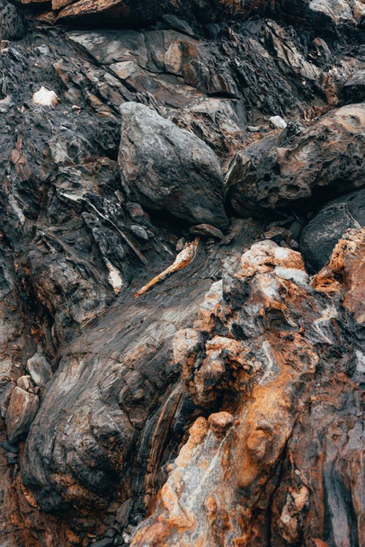 A closeup shot of a reddish-brown, black, and white rock surface - Фото, зображення