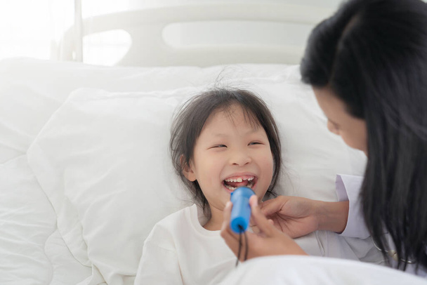 Mujer médico examinando la boca de una niña en el hospital revisando el dolor de garganta de un paciente joven
 - Foto, Imagen