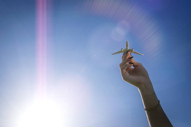 Repülőgép szárnyak a napfényes égen. Fehér repülőgép játék lány kezében repülni fényes napfény háttér. A légi jármű repülési koncepciója - Fotó, kép