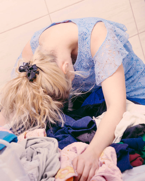 Unhappy woman in bathroom with pile of dirty clothes. Laundry concept. Hard work, dirty job, household duty. - Fotografie, Obrázek