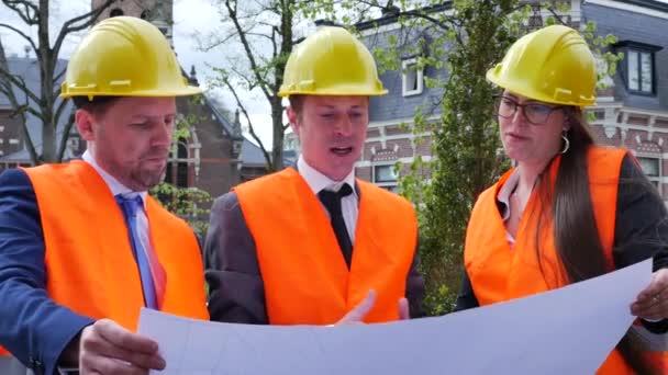 equipo de tres arquitectos en cascos discutiendo plan de proyecto - Metraje, vídeo