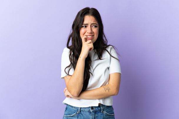 Young caucasian woman isolated on purple background nervous and scared - Photo, Image