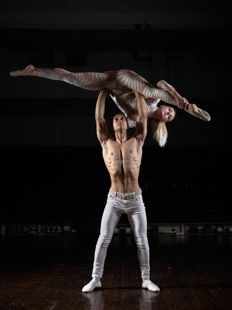 Egy pár akrobata sportoló csinálja a trükköt. Akrobaták sötét háttérrel. - Fotó, kép