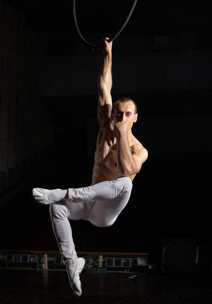 Az akrobata előad egy mutatványt a léggyűrűn. A srác meztelen felsőtesttel.. - Fotó, kép