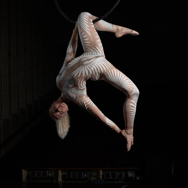 The acrobat performs a stunt on the air ring. Girl in a suit for performances. - Photo, Image