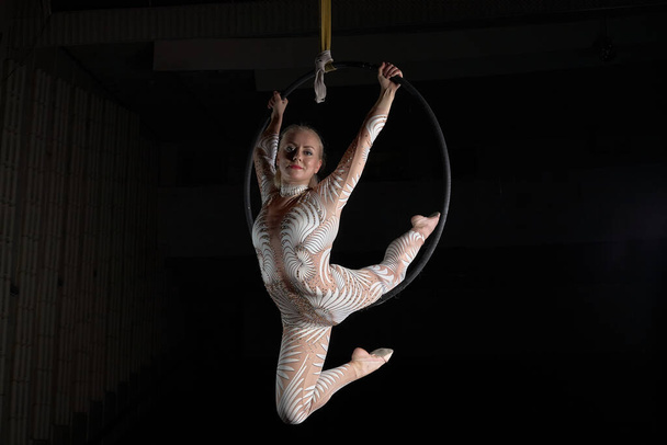 Акробат выполняет трюк на воздушном кольце. Девушка в костюме для выступлений
. - Фото, изображение