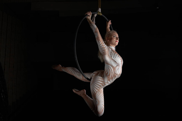 Az akrobata előad egy mutatványt a léggyűrűn. Öltönyös lány az előadásokhoz. - Fotó, kép