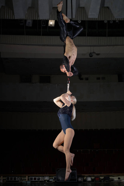 Sportovní akrobat pár předvede trik ve vzduchu. Akrobati na tmavém pozadí. - Fotografie, Obrázek
