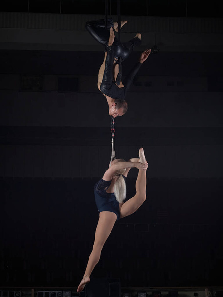 Ein Sportakrobatenpaar führt einen Trick in der Luft vor. Akrobaten auf dunklem Hintergrund. - Foto, Bild