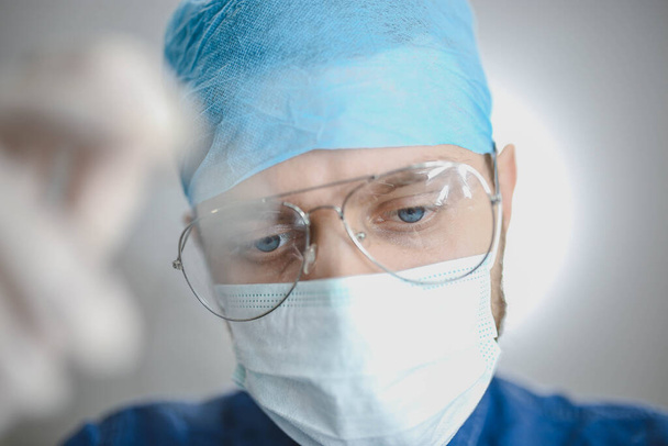 Sguardo premuroso di dottore maschile in uniforme e occhiali. Concetto di duro lavoro in medicina. - Foto, immagini