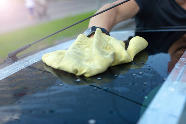 Мужчина полирует и вытирает машину тряпкой после мытья - Фото, изображение